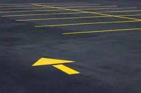 A parking lot with yellow lines and an arrow painted on the ground.